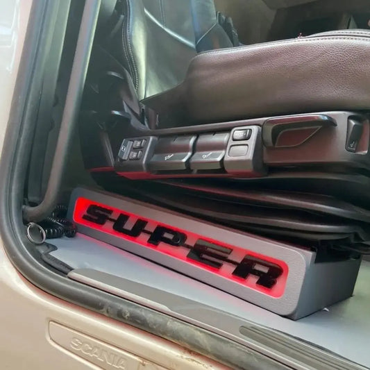 Scania Super Truck LED Seat Bases with SUPER illuminated in red, showcasing driver’s air-suspended seat and branded step sill in cab entry area.