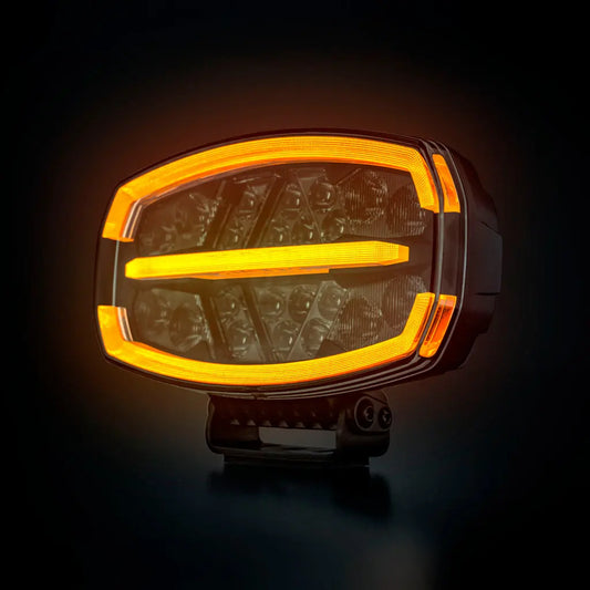FIREFLY ONE DRIVING LIGHT |STRANDS| features an oval LED design with visible LED emitters and illuminated amber light bars, ideal for off-road or utility vehicles.