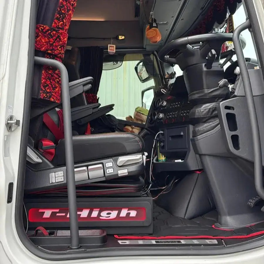 Renault T Range Truck LED Seat Bases in cab, showing driver's seat, steering wheel, red-patterned accents, and sleeper cabin entry with grab-handle.