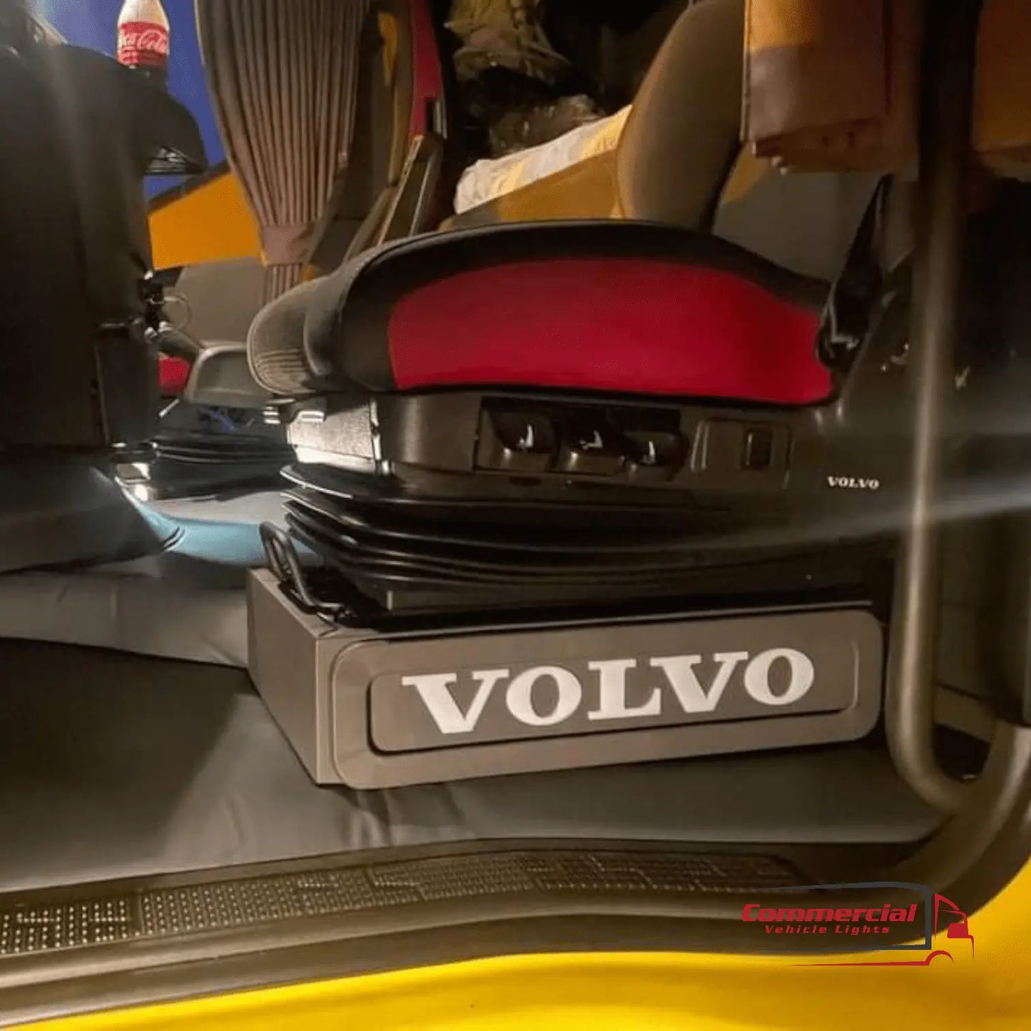 Volvo FH/FM Truck Black LED Seat Bases with armrest, adjustable controls, and suspension base featuring VOLVO logo, set in a truck cab with red seat pad.