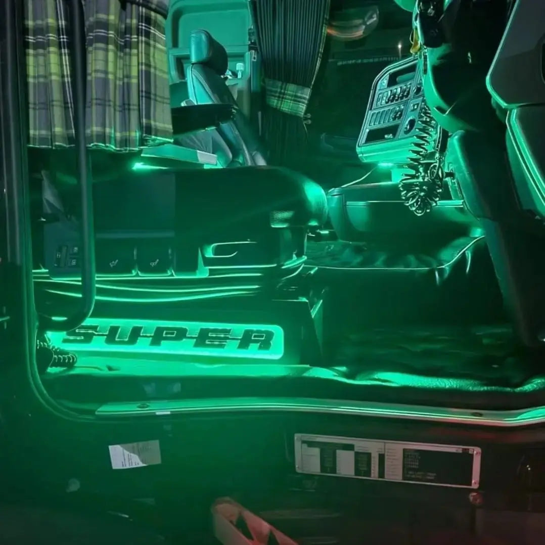 Driver’s cab showcasing Scania Super Truck LED Seat Bases (Side Lit) with green accent lighting, featuring an air-ride seat, quilted floor mat, and CB-radio handset.