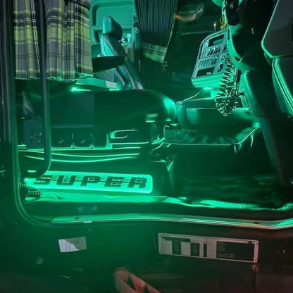 Driver’s cab showcasing Scania Super Truck LED Seat Bases (Side Lit) with green accent lighting, featuring an air-ride seat, quilted floor mat, and CB-radio handset.
