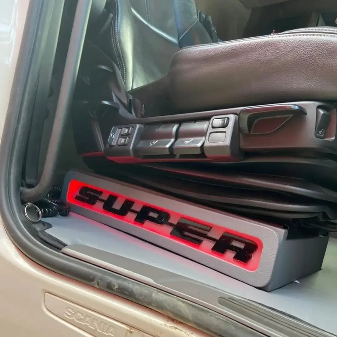 Scania Super Truck LED Seat Bases with SUPER illuminated in red, showcasing driver’s air-suspended seat and branded step sill in cab entry area.