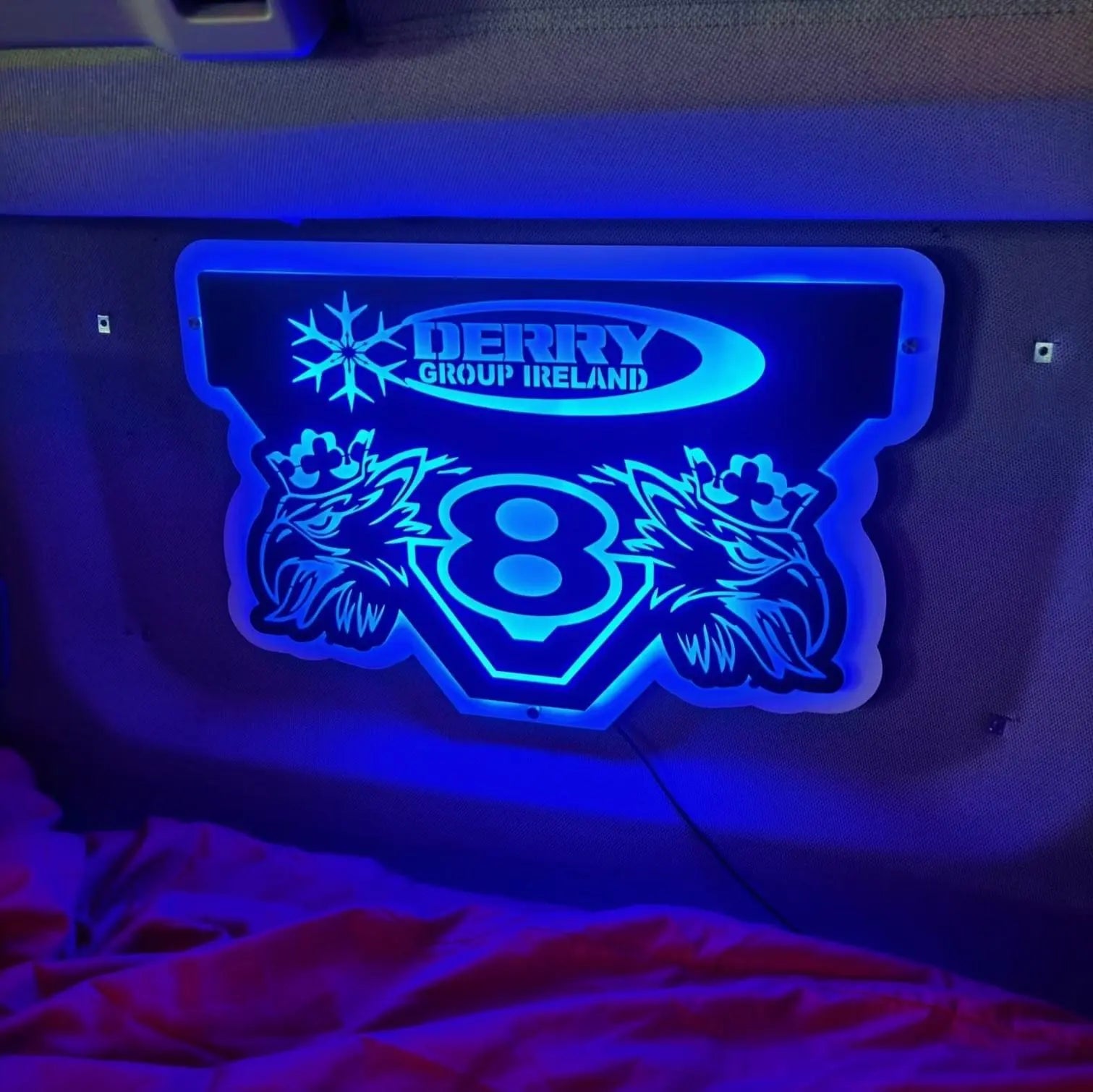 MAN 3D Truck Light Board with blue glow, mounted on cabin wall, features Derry Group Ireland and V-8 motif, power cable visible.