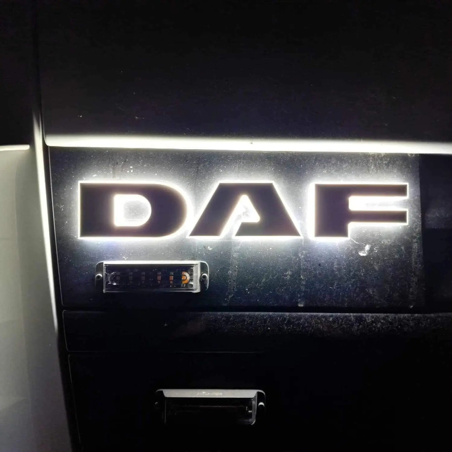 Close-up of the illuminated DAF Euro 5 LED Name Badge on a truck grille, showcasing its bright, back-lit design in acrylic and aluminum.