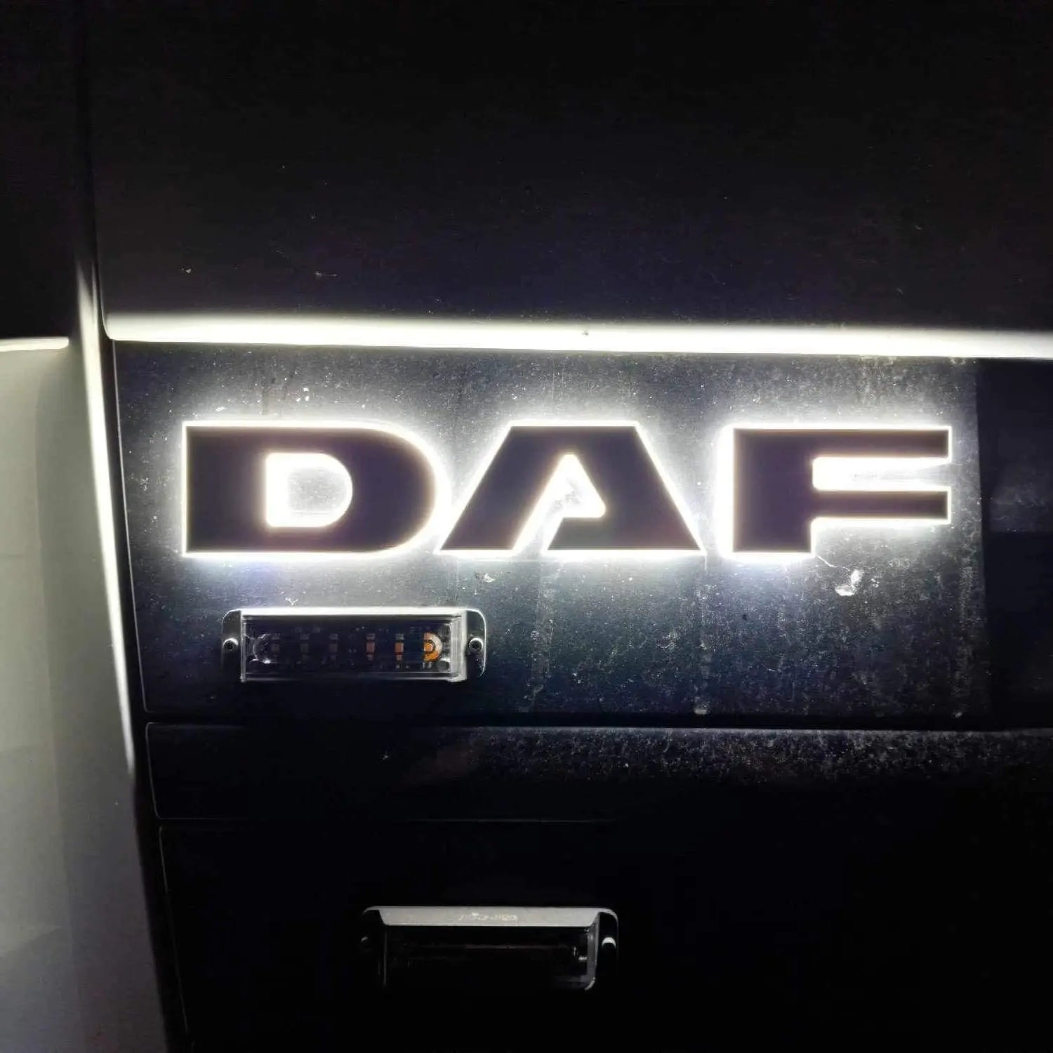 Close-up of the illuminated DAF Euro 5 LED Name Badge on a truck grille, showcasing its bright, back-lit design in acrylic and aluminum.
