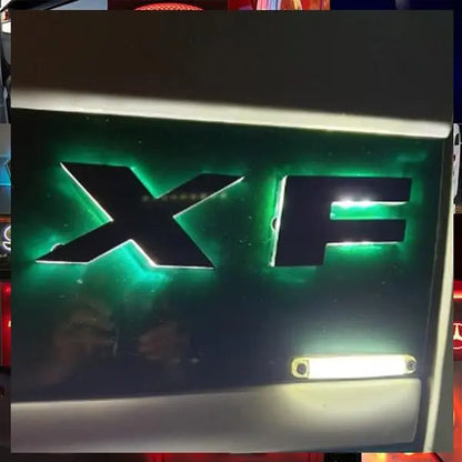 Close-up of Jaguar XF rear model badge with a small license plate lamp, showcasing the DAF Euro 5 LED Name Badge for 24V vehicles.