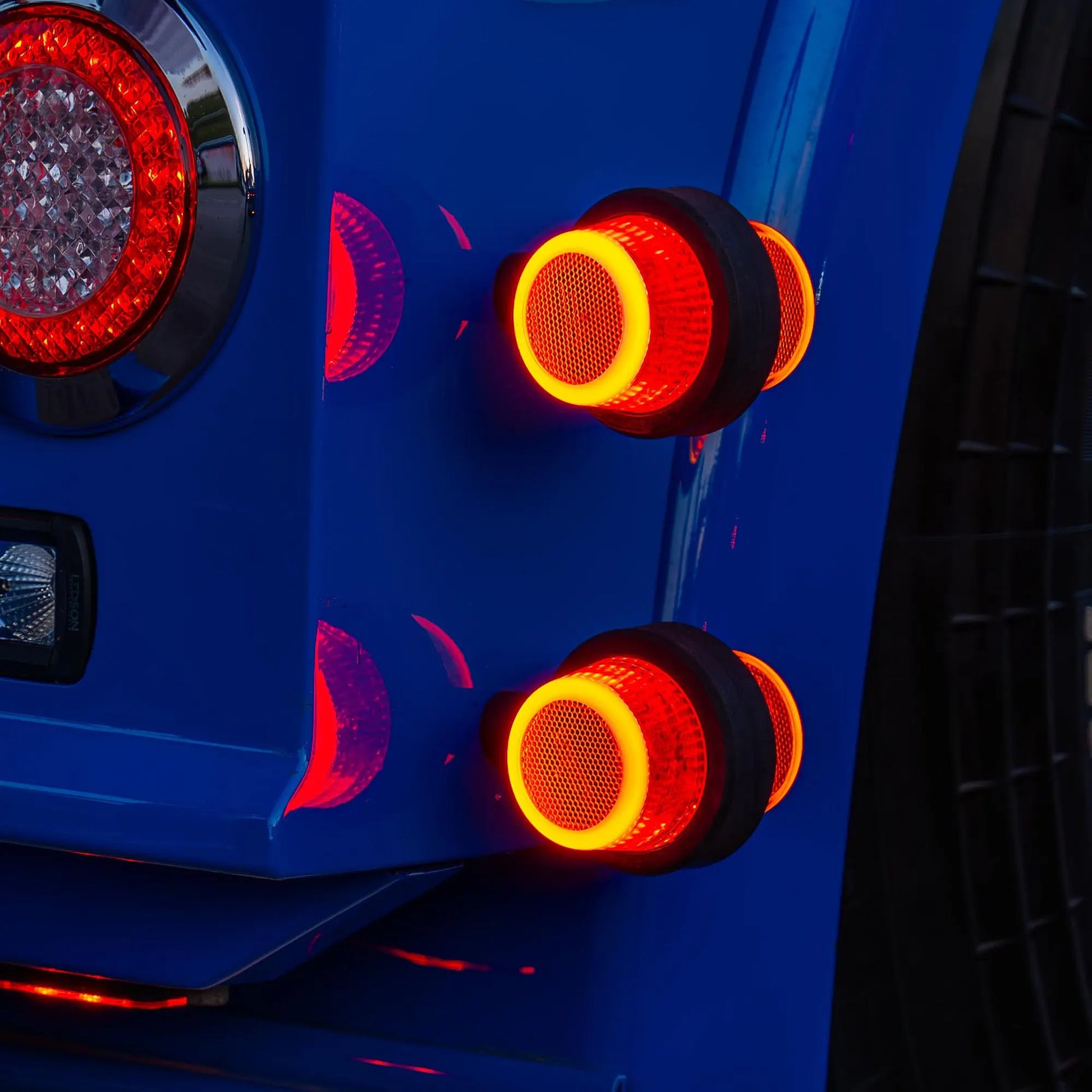 Close-up of LEDSON Halo Position Light with four circular red LED taillights, showcasing a modern design, mounted on a blue vehicle's rear panel.