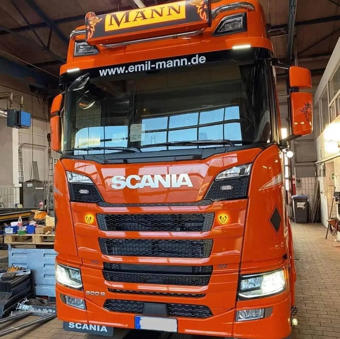 Bright orange Scania truck with MANN on sun-visor, featuring a 105x30x15cm Standard Dutch Style Illuminated LED Headboard (White LED) in a garage setting.