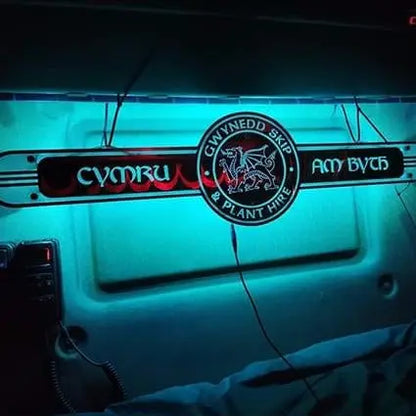 Welsh Interior Truck Mirror 1000x250mm, featuring an illuminated Welsh text sign, mounted on a truck cab bulkhead, includes CB-style microphone and bunk area below.