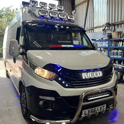 Iveco Daily with LED Back-Lit Grille Badge, showcasing bright LED lights for enhanced style and visibility, parked in a workshop with automotive tools.