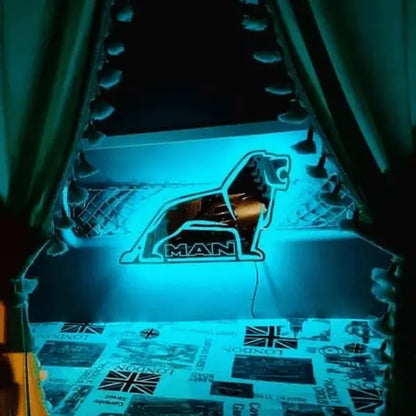 MAN Interior Truck Mirror with a glowing turquoise-blue acrylic lion logo, displayed on a windowsill with Union Jack-themed decor in the background.