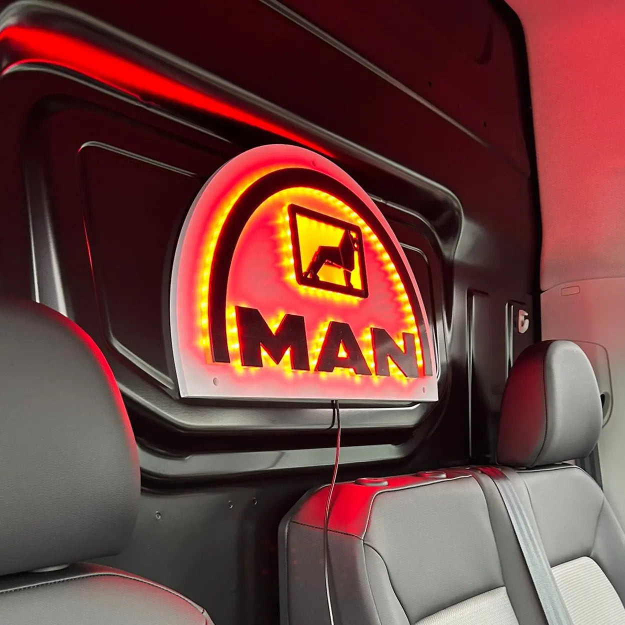 Interior of a van showing the MAN 3D Van Light Board on a bulkhead, featuring bold MAN letters, a truck icon, and backlit red LEDs.