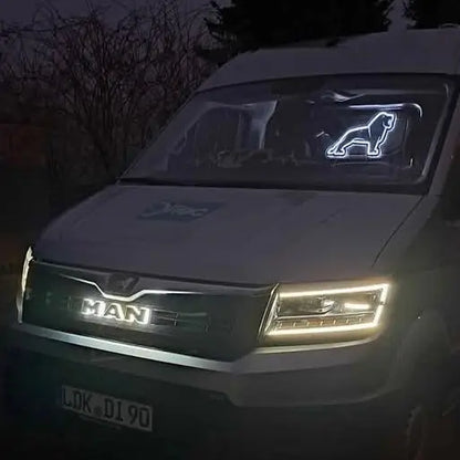 White MAN TGE van at night with LED headlights, featuring a back-lit LED grille badge shaped like a walking big cat, enhancing custom truck lighting.