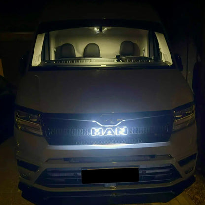 Front view of a white MAN van at night featuring the illuminated MAN TGE Grille Badge Led Back-Lit, highlighting the brand logo in the grille.