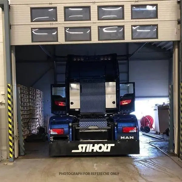 Rear view of a dark-blue MAN tractor unit in a workshop, highlighting custom LED back-lit interior door panels for 24V vehicles, shown for reference.