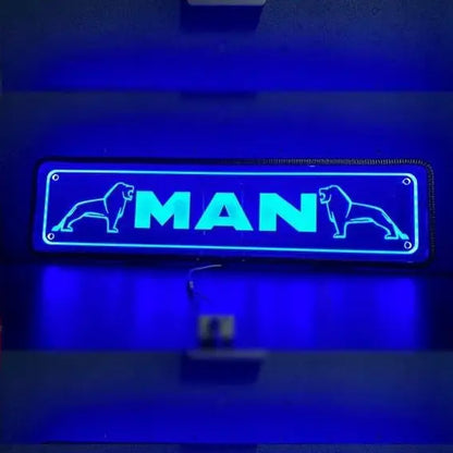 Blue neon MAN Plexi Glass Sign with stylized lions, mounted on wall with visible wires; back-lit, suitable for 12/24V vehicles, enhancing truck cabin style.