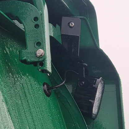 Close-up of Scania Next Gen Reduced Wind Kit Work Light Mounts, showing adjustable hinge and LED mount, wet from rain.