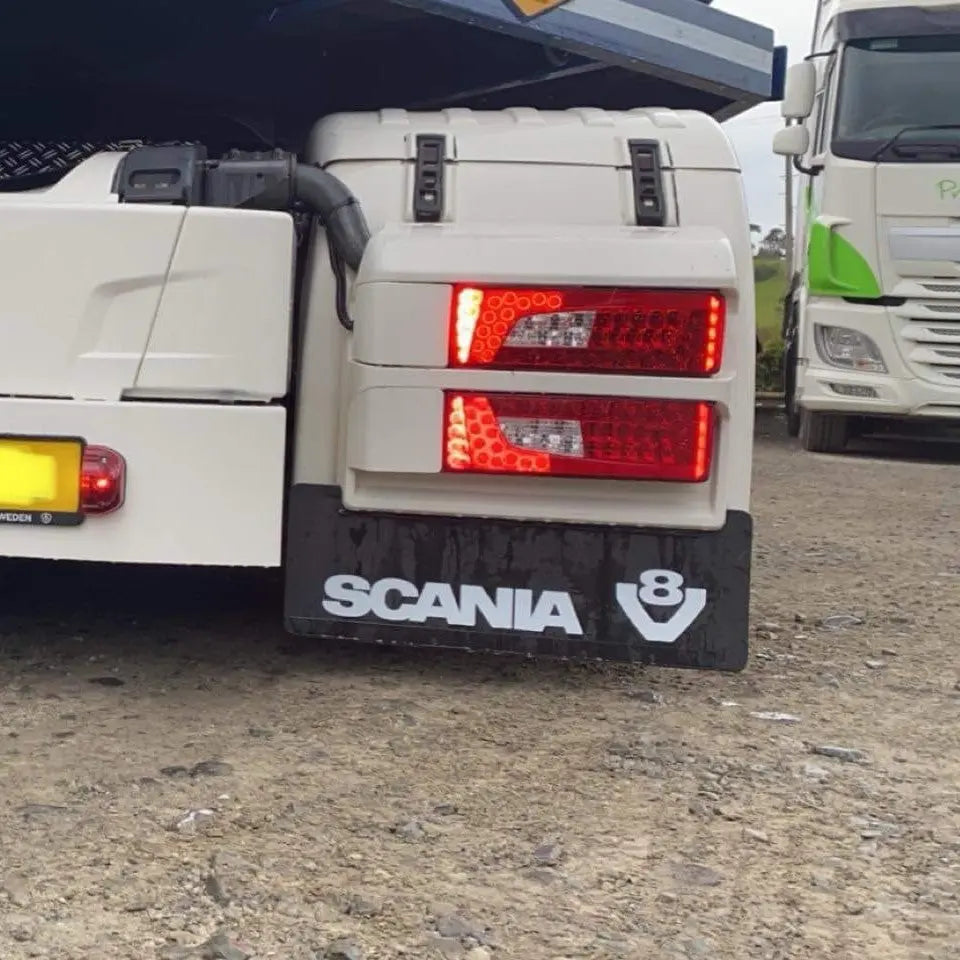Close-up of Scania Rear Double Light Plug Cover, stainless steel, fitted over light plugs, enhancing truck aesthetics and protection. Visible taillights and branded mudflap.