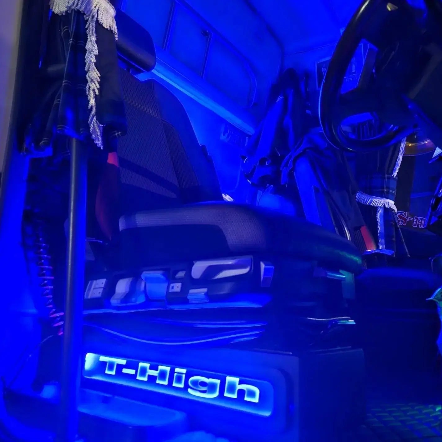 Renault T Range Truck LED Seat Bases (Side Lit) highlighted in blue lighting, showcasing upholstery, suspension base, steering wheel, and coiled wiring within a tractor cab.