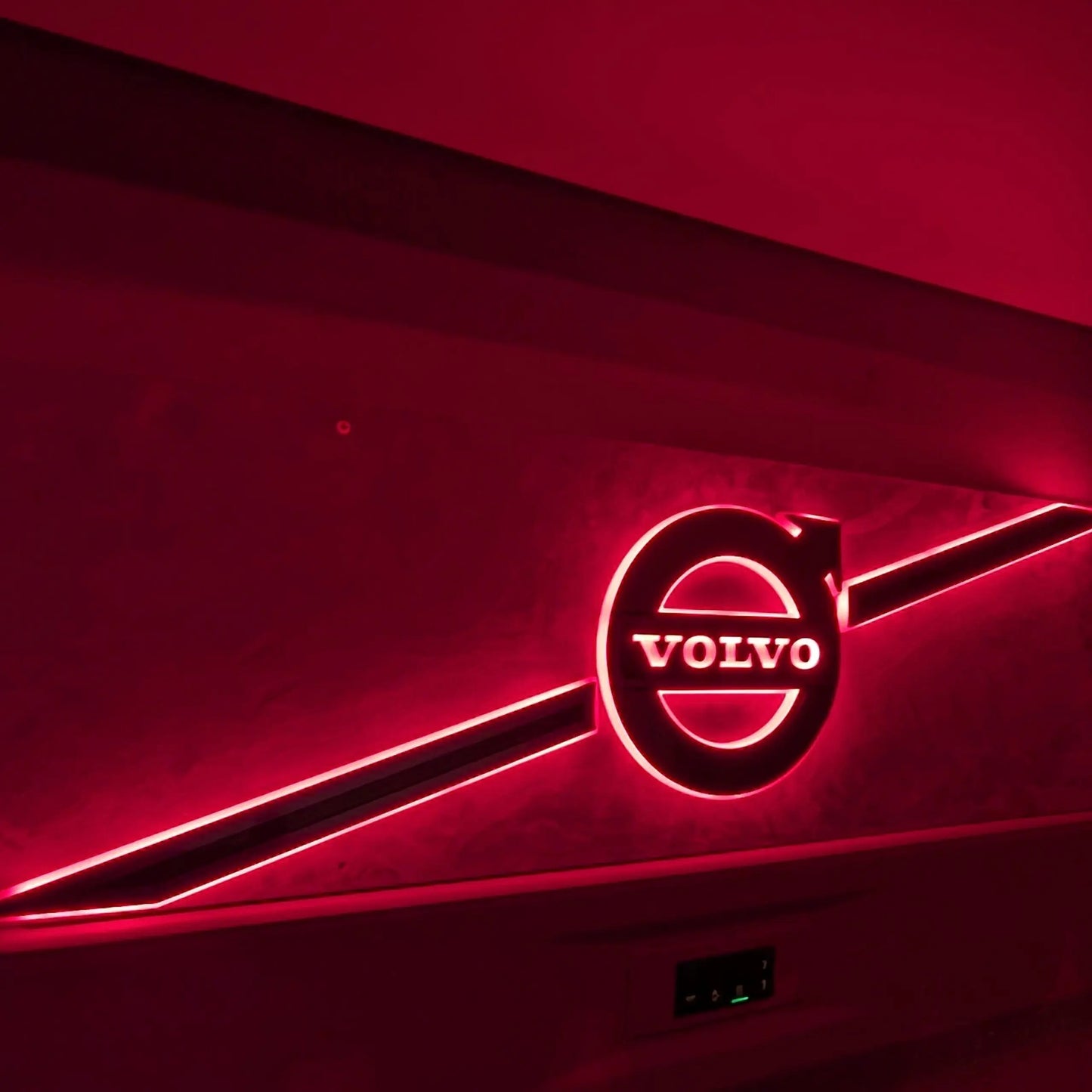 Volvo Badge LED Truck Light Board by TLD, featuring a stylized neon-lit Volvo logo with red glow and diagonal light bars, mounted on a wall.
