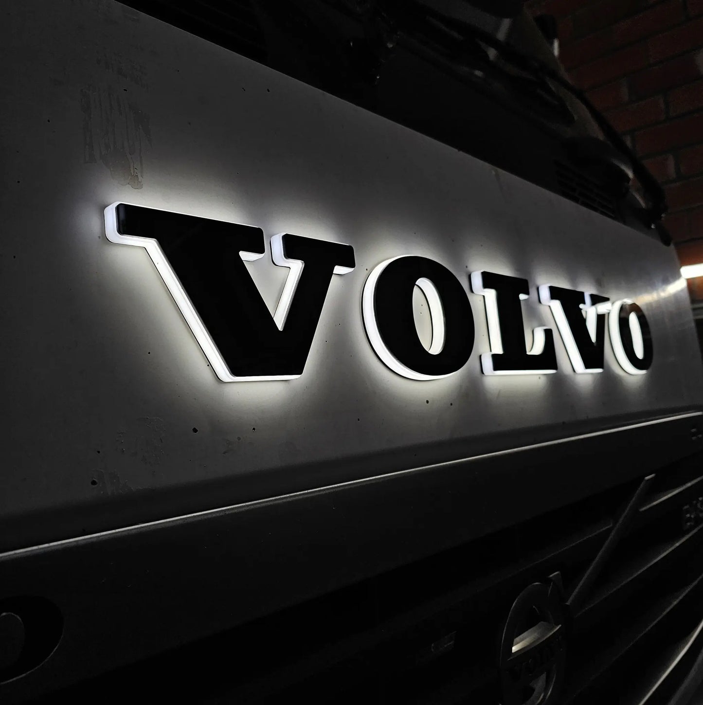 Close-up of the illuminated VOLVO nameplate on a truck grille, showcasing the Volvo Grille Badge LED Back-Lit with strong, bright light.